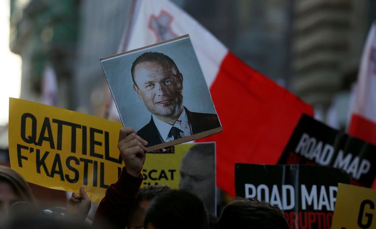 Een betoger houdt een foto de lucht in van een half onder het bloed bedekte Joseph Muscat, toen – in 2019 – nog eerste minister van Malta.  Beeld REUTERS