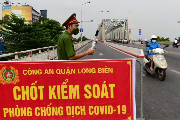 In Hanoi, de hoofdstad van Vietnam, controleert deze politieman het verkeer bij een coronacheckpoint. Een groot deel van het land is in lockdown door de snelle verspreiding van de deltavariant.