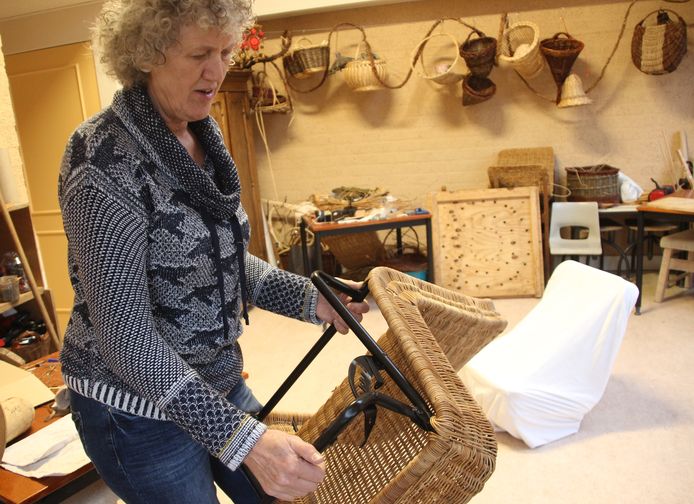 Mandaniet, vlechtster Anita van Kraaij uit Veghel, laat de lastig bereikbare plekjes zien aan de onderkant van de rotan stoel van de DAF-kini.