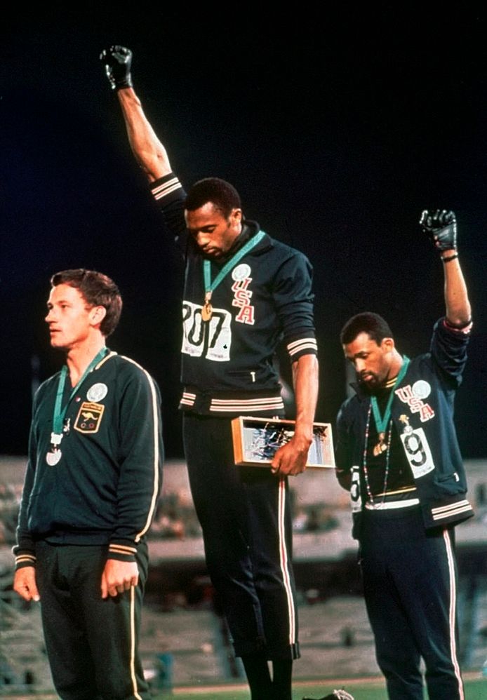 Het beroemdste podiumprotest ooit: Tommie Smith (m) en John Carlos (r) maken het black power-gebaar op de Spelen van 1968. De twee Amerikanen werden ervoor geschorst.