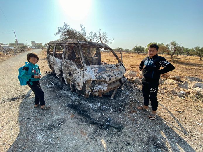 Kinderen staan bij een uitgebrande auto nabij de gebombardeerde site in Barisha.