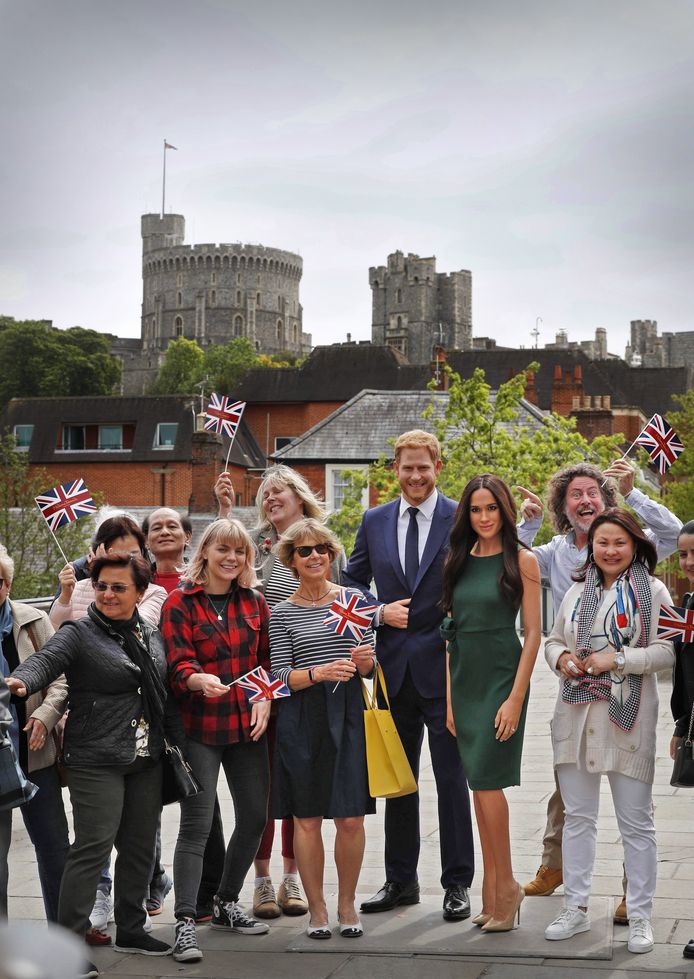 Bezoekers aan Windsor poseren bij het kasteel met wassen beelden van prins Harry en Meghan Markle.