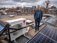 Jan van der Meer bij de buiteninstallatie van z'n warmtepomp, omringd door zonnepanelen en een zonnecollector.