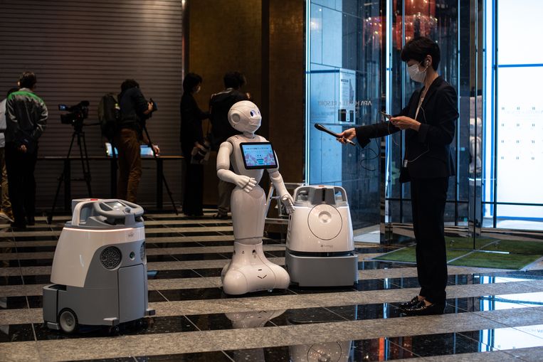 Robot ‘Pepper’ en twee schoonmaakrobots in de lobby van een hotel in Tokio. Beeld AFP