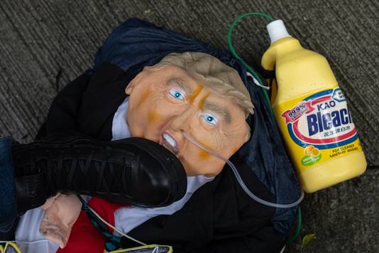 Een demonstrant voor het Amerikaanse consulaat in Hongkong trapt op een op president Trump lijkende pop, waaraan een fles chloorbleekmiddel vastzit. 