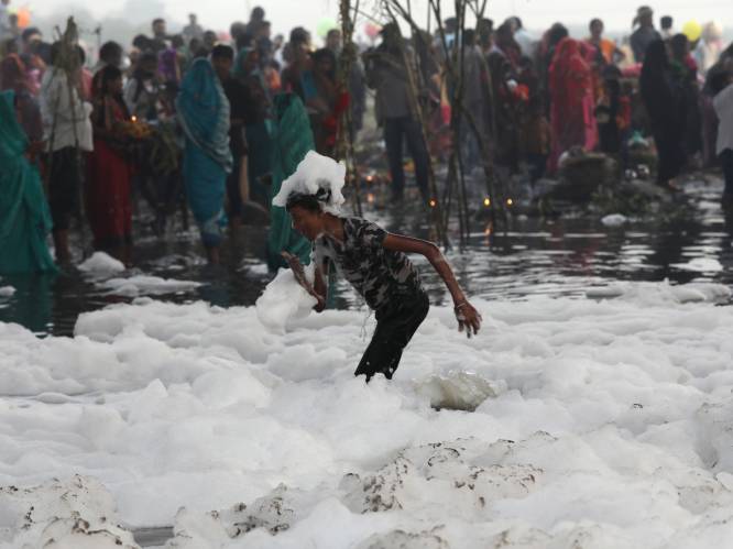 Hindoes baden in rivier bedekt met giftig schuim