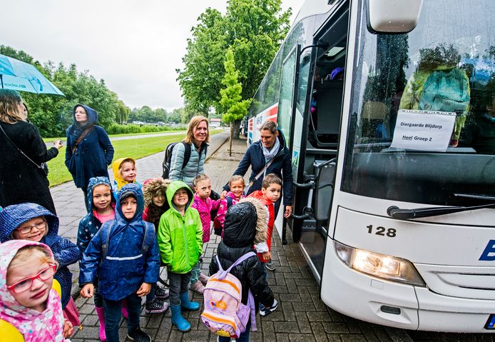 Kinderen gaan op schoolreisje, de ouders zwaaien hen uit.