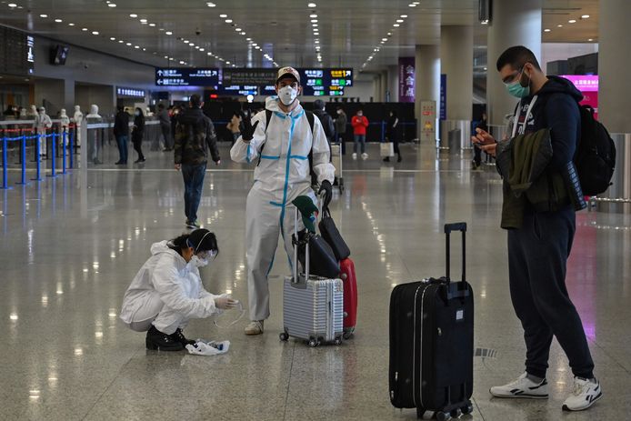 Passagiers met beschermende pakken op de internationale luchthaven van Shanghai.