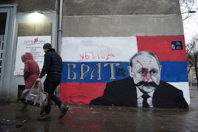 People walk past a mural of Russian President Vladimir Putin in the Serbian capital Belgrade on Sunday, which has the word 