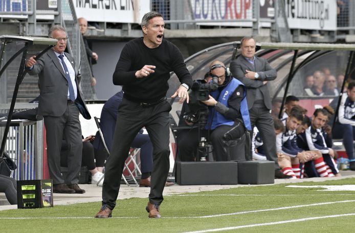 FC Dordrecht-trainer Gerard de Nooijer druk coachend, terwijl Dick Advocaat van Sparta op de achtergrond ogenschijnlijk rustig de wedstrijd volgt.