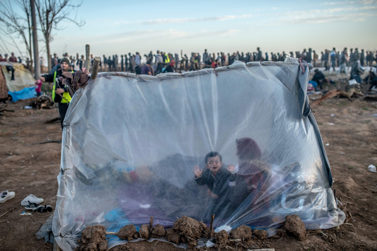 Een Syrische vrouw wacht met haar zoontje in een tent op voedsel in het niemandsland tussen Turkije en Griekenland. Vluchtelingen zijn inzet geworden van een politiek steekspel in de regio. Beeld  Bulent Kilic / AFP