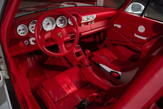 Het rode interieur van een witte Porsche.