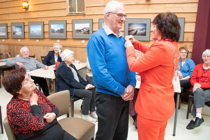 Bram de Ruijter ontvangt in Schoondijke een lintje uit handen van burgemeester Marga Vermue. Naast hem zijn vrouw Saar.