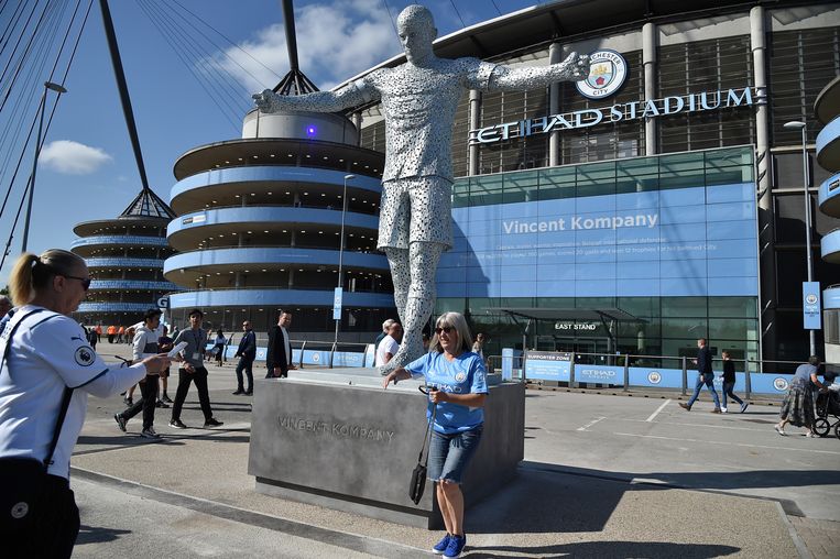 Een Manchester City-fan gaat op de foto bij het standbeeld van Vincent Kompany voor het Etihad-stadion. Beeld AP