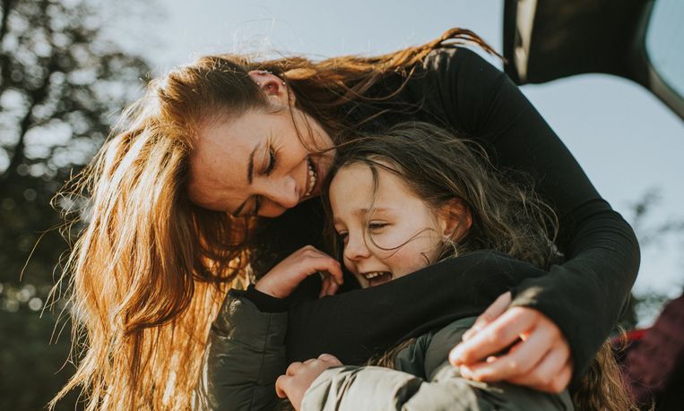 A young Mum bends over to her daughters height, and wraps her arms around her. They both wear thick winter coats as they brace the cold weather, and warm up in a loving embrace. Beeld Getty Images
