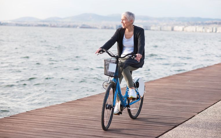 Active mature-senior woman riding bicycle in the city Beeld Getty Images