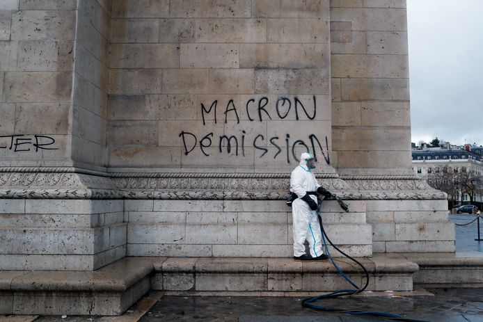 Een schoonmaker haalt tegen Macron gerichte graffiti op de Arc de Triomphe weg, die zaterdagavond is aangebracht.