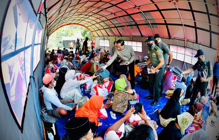 Indonesisch president Joko Widodo (m.) deelt voedselpakketten uit aan mensen die hun huizen kwijt zijn. Beeld EPA