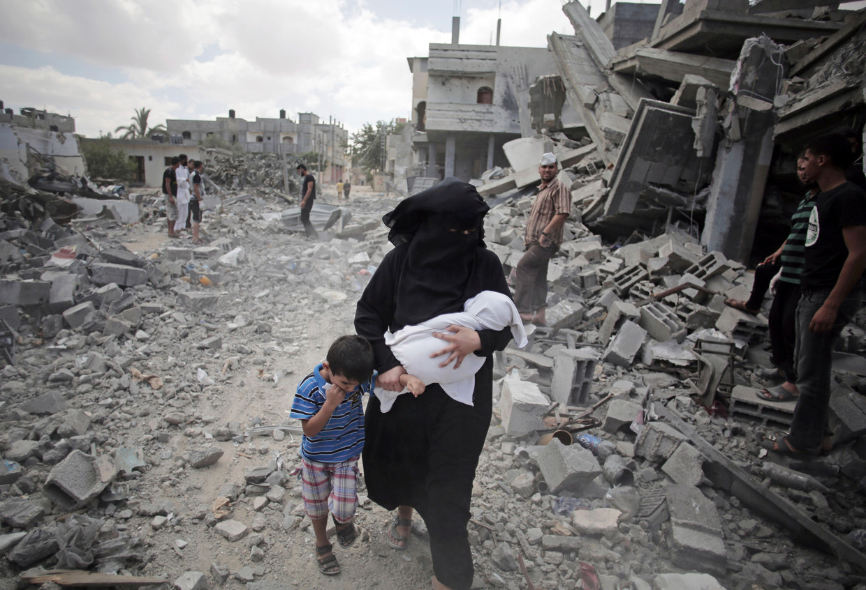Een Palestijnse vrouw loopt in 2014 langs de puinhopen van gebouwen die zijn getroffen door Israëlische luchtaanvallen. Beeld AP
