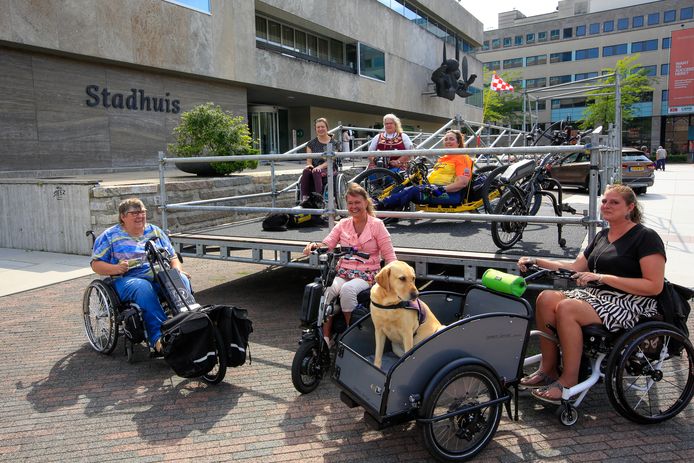Rolstoelers op en bij de tijdelijke hellingbaan bij het Stadhuis in Eindhoven. Links Pia Hendriks. Op de hellingbaan staat rechts Ingrid Schoenmakers en in het midden Anneke Smit