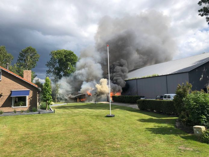 Vlammen slaan uit de schuur en bedreigen de grote loods. Gelukkig slaat het vuur niet over.