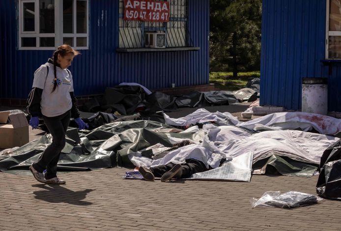 Een vrouw loopt voorbij de lichamen van slachtoffers van de raketaanval op het station van Kramatorsk, terwijl 700 km westwaarts Ursula von der Leyen en Josep Borrell met de trein aankwamen in Kiev voor een ontmoeting met president Zelensky.