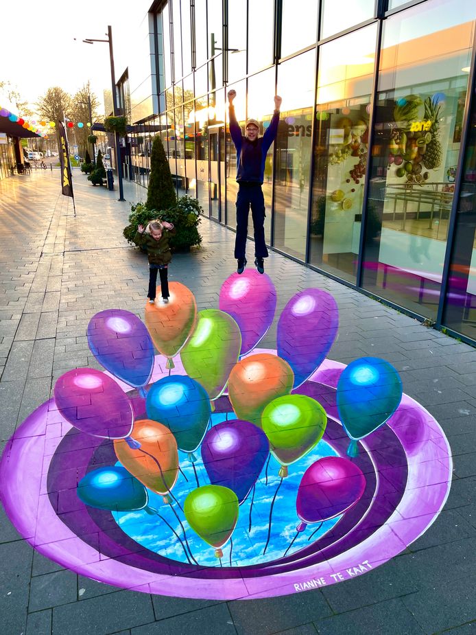 Twee bezoekers aan het winkelcentrum poseren met de schildering.
