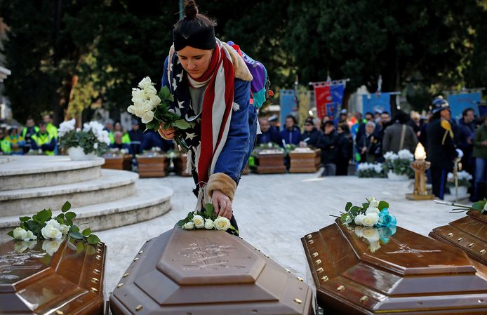 Een Italiaanse vrouw legt een roos op een van de kisten van de 26 Nigeriaanse vrouwen die vorige week stierven bij hun vlucht naar Europa. Ze worden begraven op de begraafplaats van Salerno. Foto Ciro De Luca