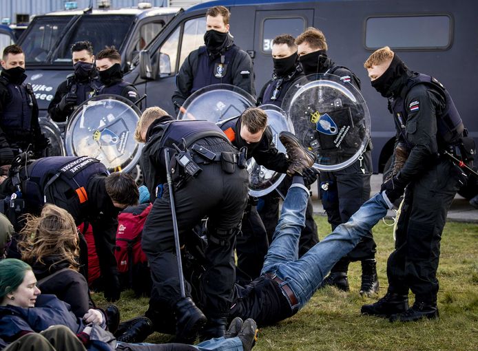 Een klimaatactivist van Extinction Rebellion wordt aangehouden tijdens een actie bij Eindhoven Airport.