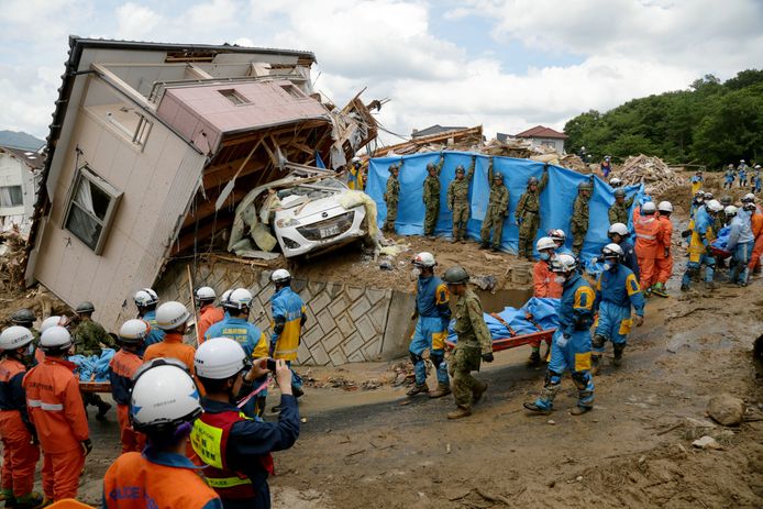 Reddingswerkers dragen een slachtoffer weg nadat die om het leven kwam door een landsverschuiving die werd veroorzaakt door zware regenval in Kumano in de prefectuur Hiroshima.