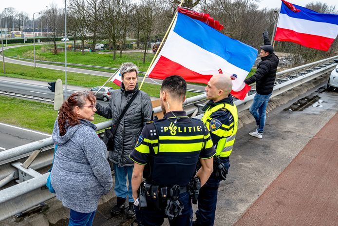 Een drietal demonstranten protesteert op een viaduct boven de A59 bij Raamsdonksveer tegen het kabinetsbeleid.