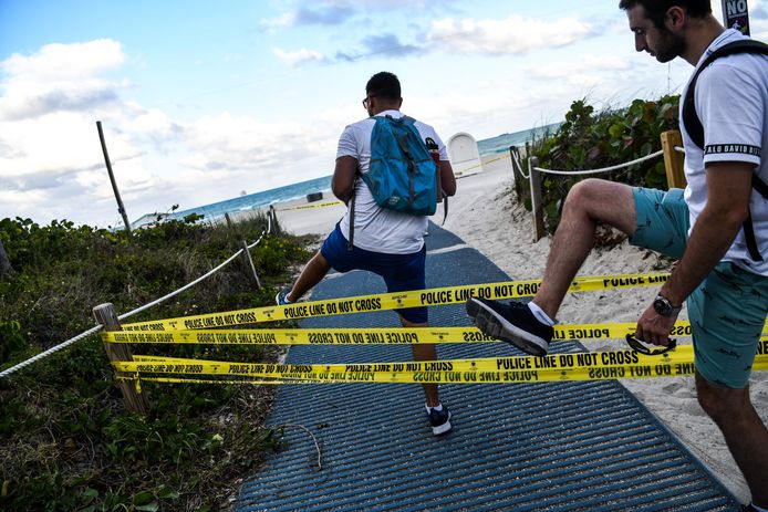 Mannen stappen over de politielinten die de toegang tot Miami Beach moeten verhinderen.