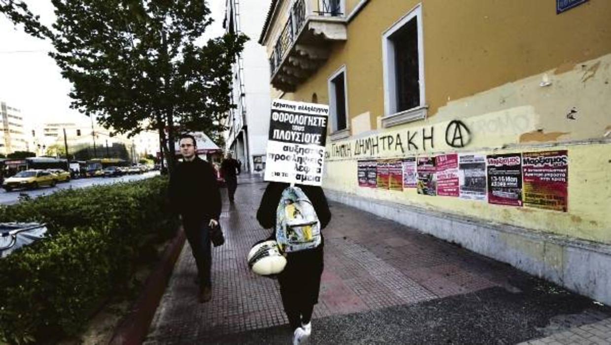 Een actievoerder draagt een bord met de tekst 'belast de rijken', onderweg naar een demonstratie in Athene tegen de bezuinigingen. (FOTO EPA) Beeld 