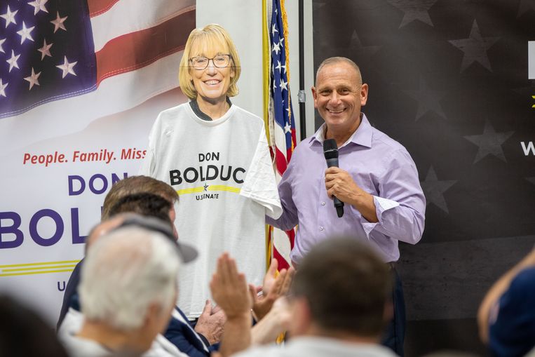 Don Bolduc, de Republikeinse Senaatkandidaat in New Hampshire, voert campagne naast een kartonnen bord van zijn Democratische opponent Maggie Hassan, de zittende senator . 
 Beeld Getty Images