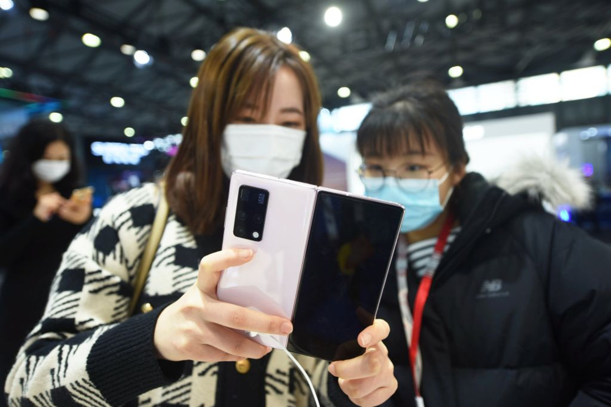 Bezoekers houden een telefoon van Huawei  vast tijdens het Mobile World Congress 2021 in Shanghai Beeld Barcroft Media via Getty Images