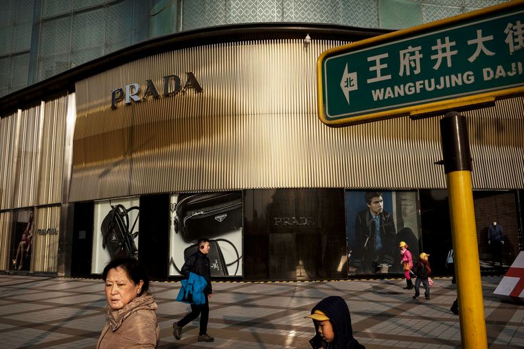 Voetgangers passeren een luxe Prada-winkel in het centrum van Beijing, China.  Beeld Kevin Frayer / Getty