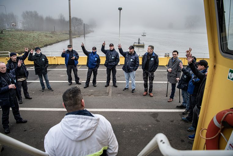 FNV-bestuurder Nuri Alders (op de rug gezien) spreekt de stakende veermannen toe op de pont in Appeltern. Beeld Koen Verheijden