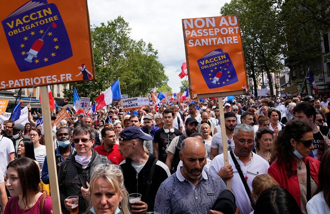 Protestors hold up signs that read 'no to the vaccine passport' during a demonstration in Paris, France, Saturday, July 31, 2021. Demonstrators gathered in several cities in France on Saturday to protest against the COVID-19 pass, which grants vaccinated individuals greater ease of access to venues. (AP Photo/Michel Euler)