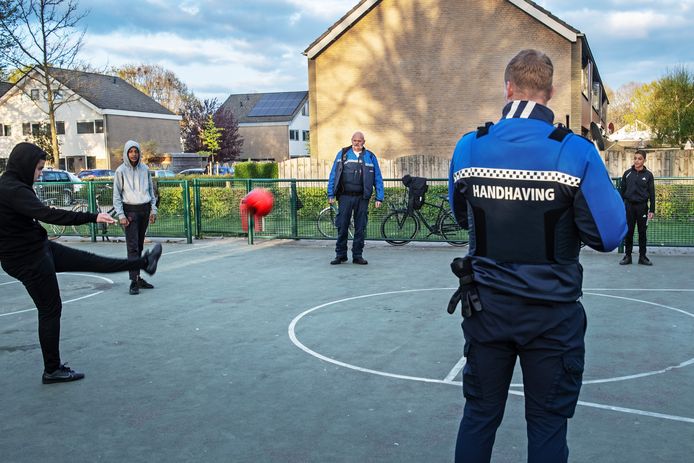 Jongeren in Druten-Zuid trappen een balletje met handhavers van de Werkorganisatie Druten-Wijchen. Wijchense jongeren wordt binnenkort gevraagd mee te denken over de coronasamenleving.