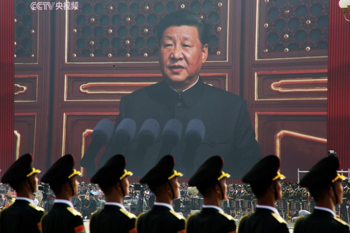 Chinese soldaten kijken tijdens een militaire parade naar een gigantisch scherm, terwijl Xi Jinping een toespraak houdt.