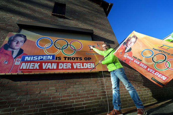 Patrick de Rooij bij het grote bord en vlag van olympisch dorpsgenoot Niek van der Velden.