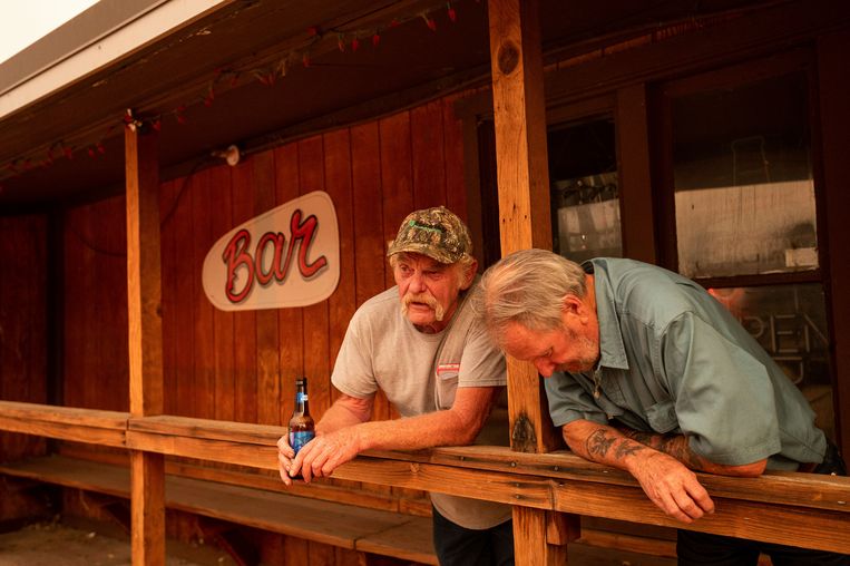 Dave Ferner (l.) en Bob Prary (r.) kijken toe hoe de bosbrand voorbij hun stadje Doyle, Californië, raast. Prary verloor zijn woning vorig jaar in een bosbrand. Beeld AP