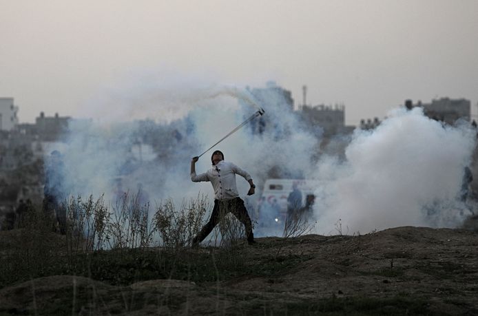 Een Palestijn gooit Israelisch traangas terug bij de grens tussen Israël en de Gazastrook.