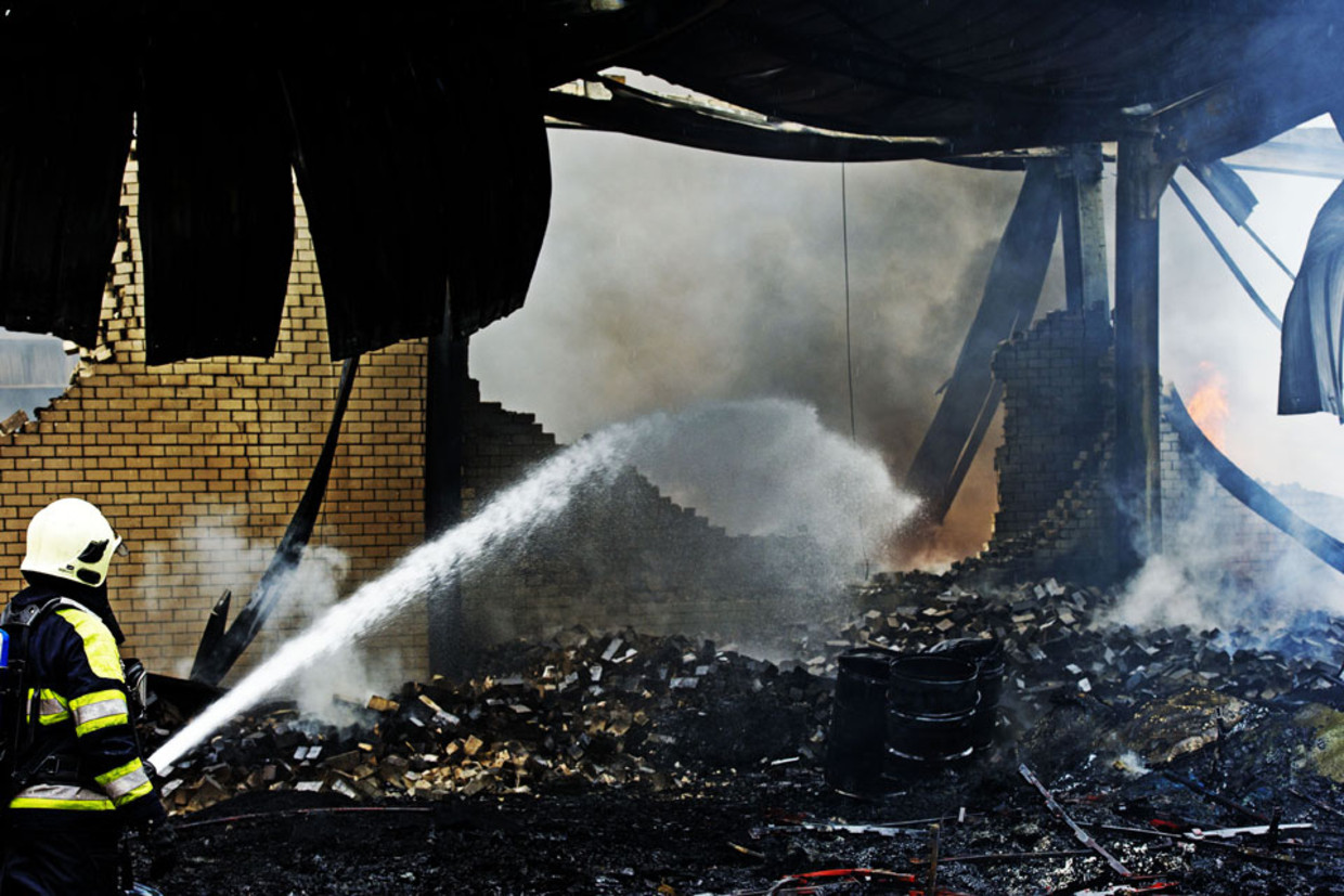 Brandweermannen zijn woensdag op industrieterrein De Vest in Valkenswaard bezig met het blussen van een grote brand. (ANP) Beeld 