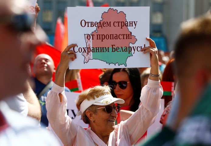 Een vrouw houdt een bord vast op de pro-Loekasjenkobetoging met de tekst: "Laten we het land van de afgrond weghalen! Laten we Wit-Rusland redden!"