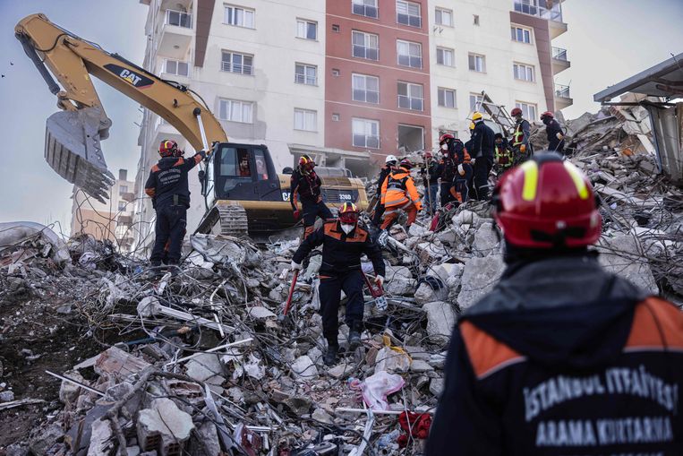 Reddingswerkers zoeken naar lichamen van slachtoffers onder het puin van een ingestort gebouw in Turkije.  Beeld AFP