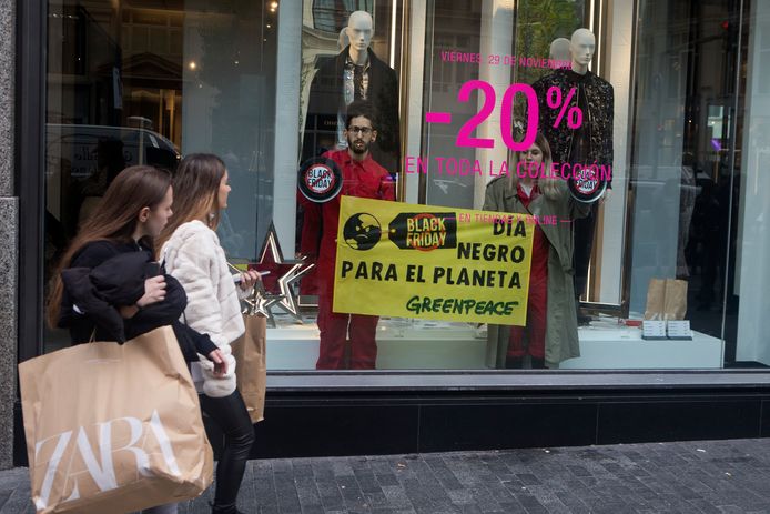 Shoppers in Madrid zien activisten van Greenpeace in een etalage. Hun boodschap: Black Friday is een zwarte dag voor de planeet.