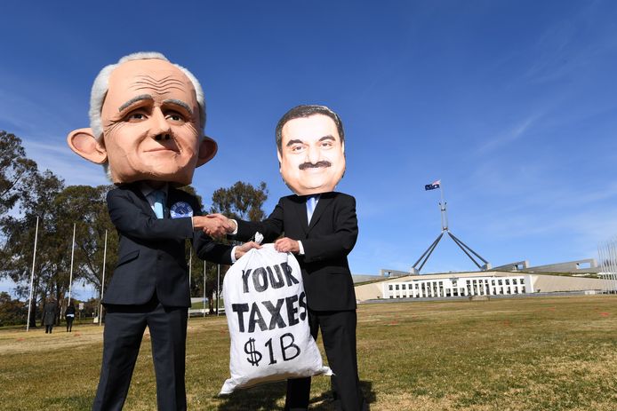 Actievoerders met maskers die de Australische premier Malcolm Turnbull (links) en Adani-baas  Gautam Adani voorstellen, voeren actie voor het Australische parlement in hoofdstad Canberra. Foto uit 2017.