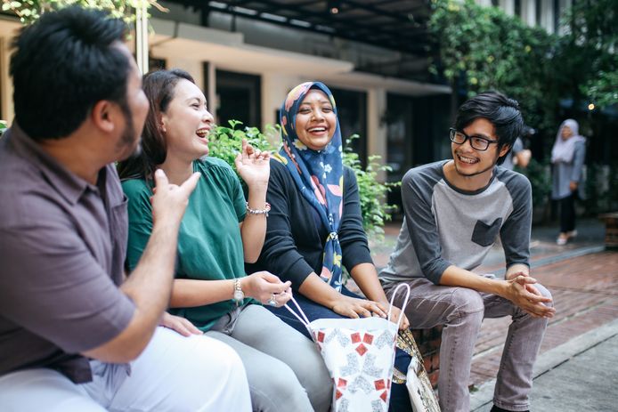 Young people talking on the street of Kuala Lumpur, having a break together in front of their office.