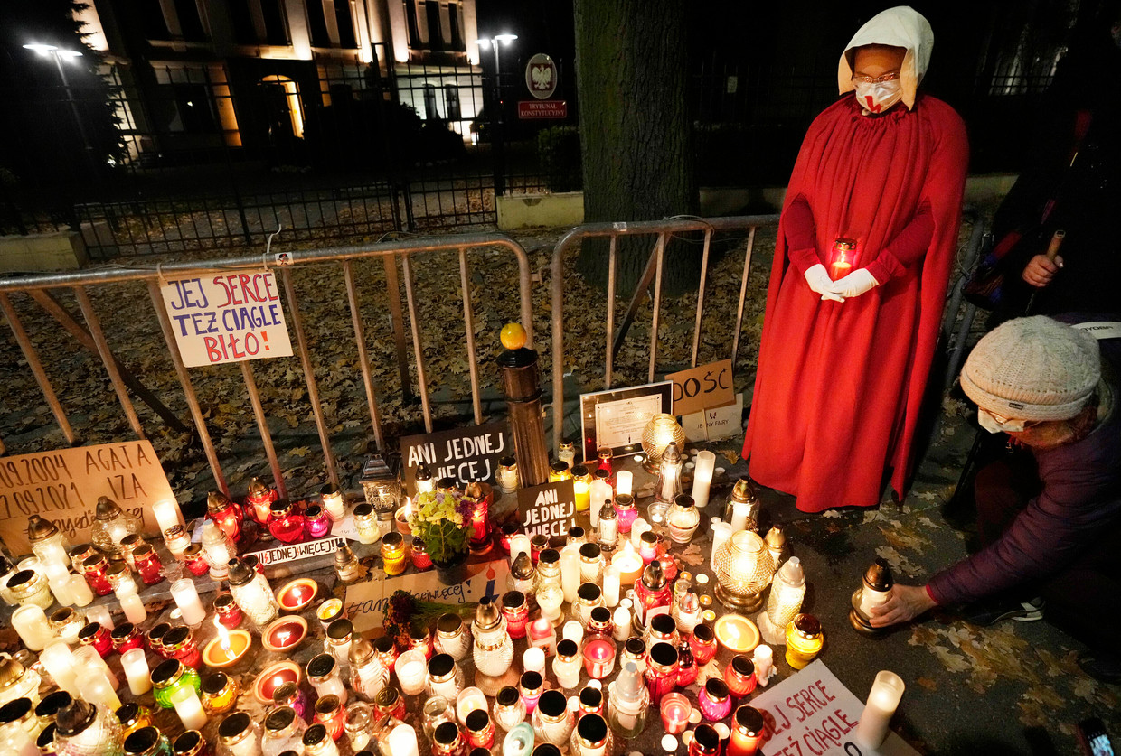 Mensen branden kaarsen ter nagedachtenis van Izabela. Een manifestante verkleedde zich als een dienstmeid uit de dystopische serie 'A Handmaid's Tale', waarin vrouwen toegewezen worden aan mannen met het enige doel om hen kinderen te baren. Beeld AP